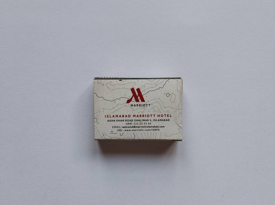 Islamabad Marriott Hotel logo with contact details and contour map pattern