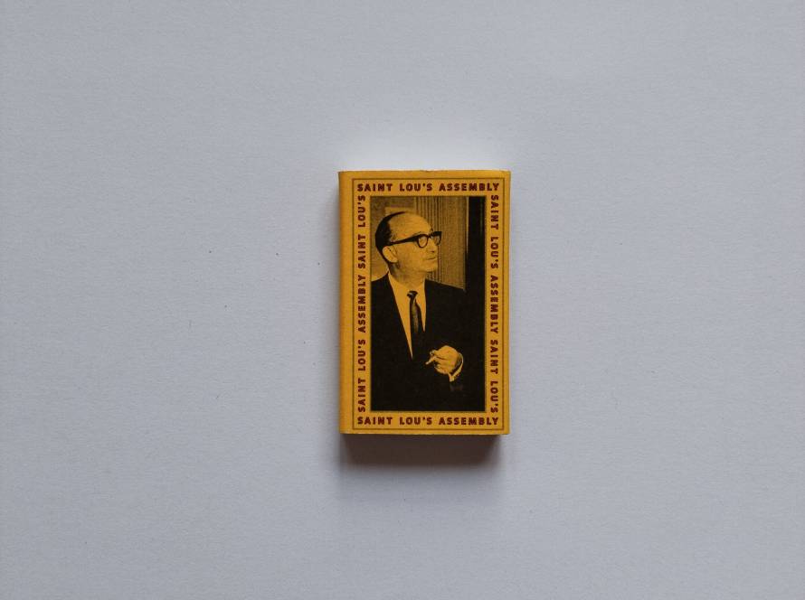 Matchbox from Saint Lou's Assembly in Chicago. Yellow border with portrait and text-heavy back design.