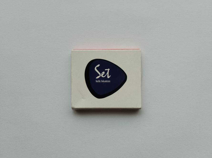 “Set Balık Lokantası” branded promotional matchbox; minimalist white design with blue logo emblem