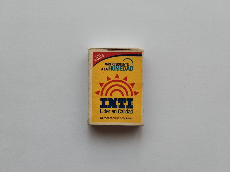 INTI brand safety matches; yellow front with sun logo and “Más resistente a la humedad” text, back featuring Deli Arroz food advertisement and Peruvian manufacturer details