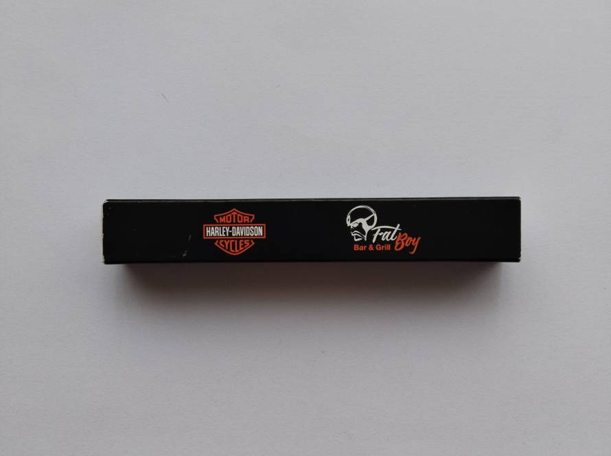 Harley-Davidson Cycles & “Fat Boy Bar & Grill” co-branded promotional matchbox; black design with orange logo and skull graphic. Reverse includes phone number and website addresses.