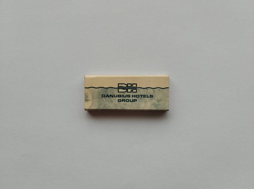 “Danubius Hotels Group” promotional matchbox with wave motif and corporate DH logo. Reverse includes phone number (+36 1 888 8200) and danubiushotels.com website.