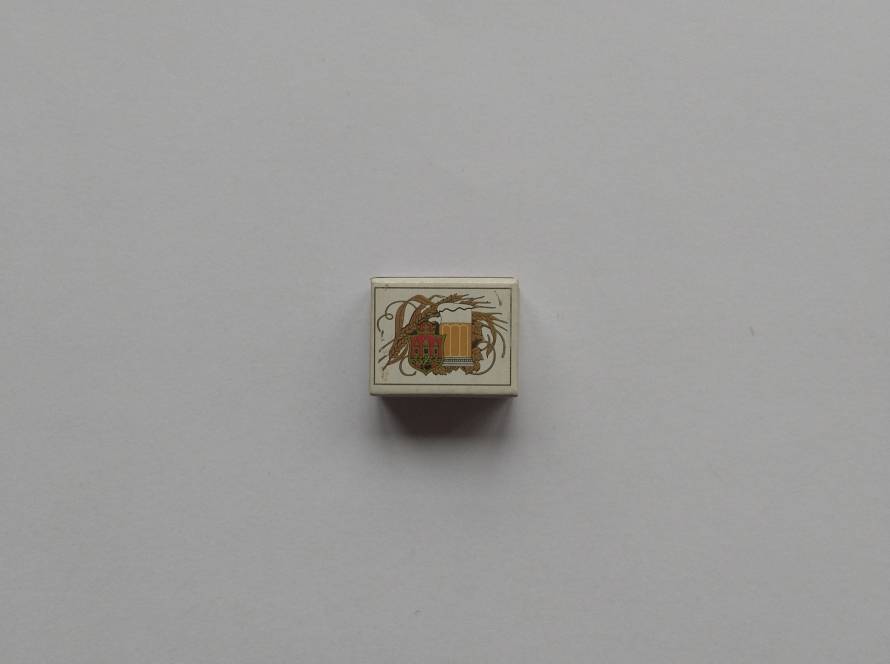 Matchbox featuring beer mug, barley, and crest illustration. Likely associated with brewery or beer brand promotion.
