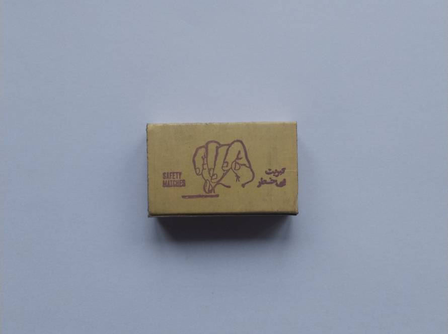Matchbox labeled AZAD Safety Matches with Arabic script and instructional striking illustration. Regional consumer product with bilingual design.