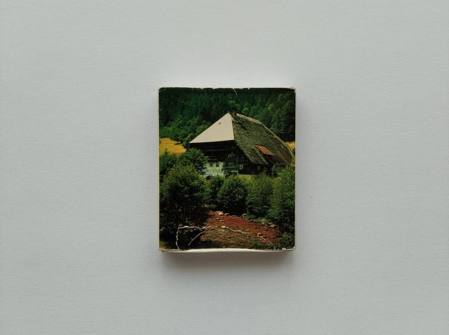Scenic matchbox featuring a traditional Black Forest farmhouse surrounded by forest and stream.