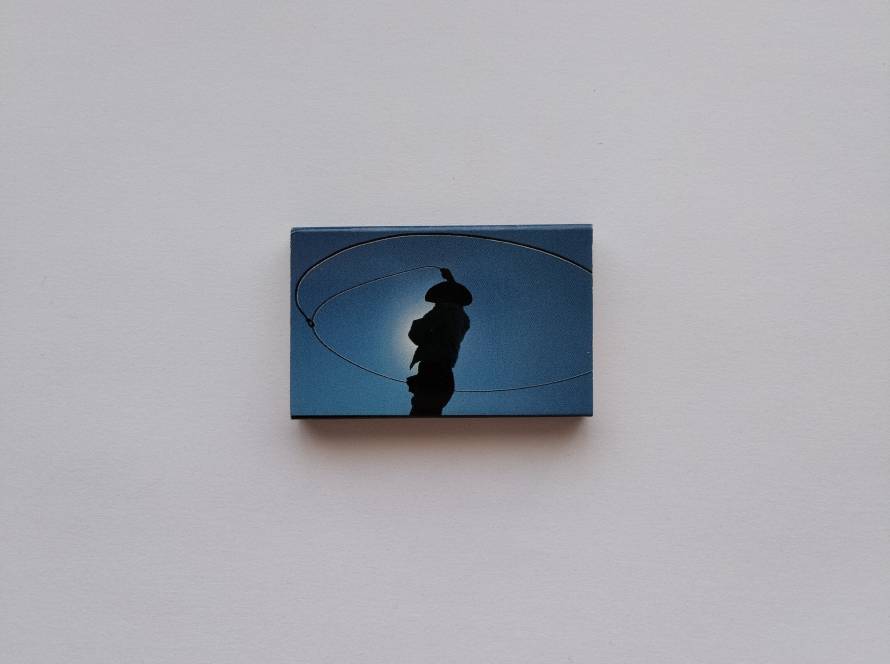 Minimalist design featuring silhouette of a cowboy spinning a lasso against a blue gradient background.