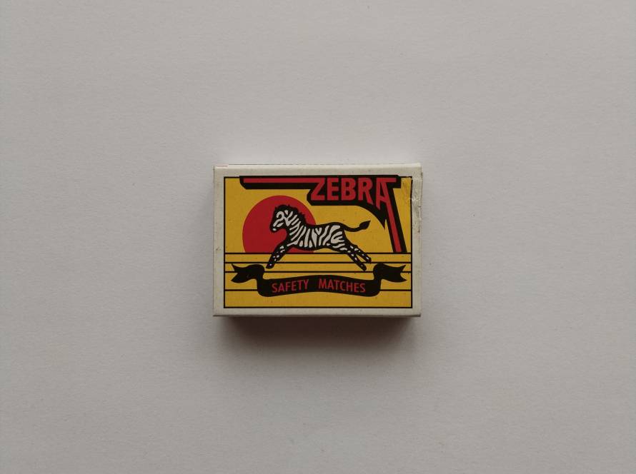 “Zebra” Safety Matches box with bold yellow ground, red sun disc and zebra illustration, representing a modern revival of traditional animal-branded match packaging design.