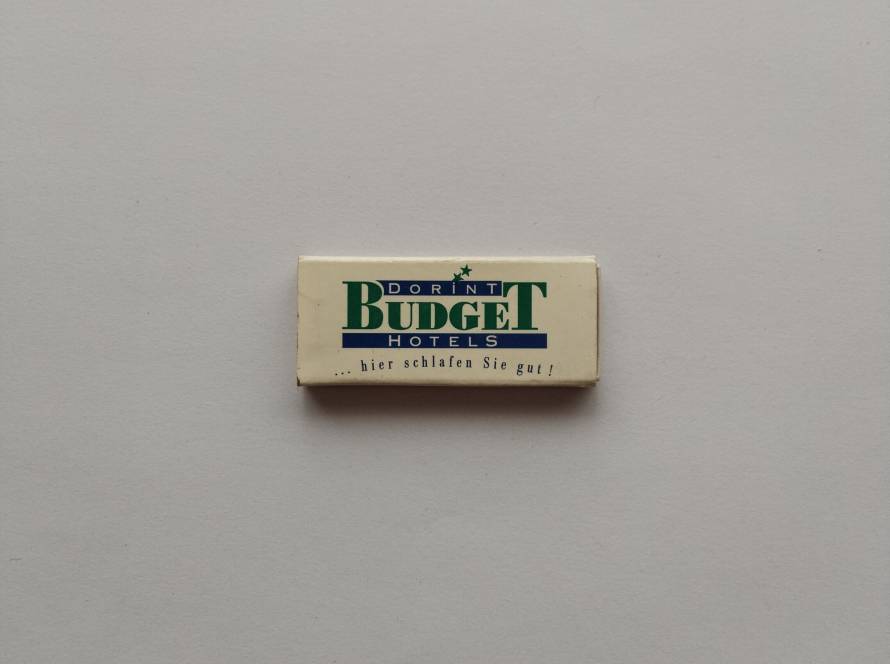 Dorint Budget Hotels promotional matchbox featuring green-blue corporate logotype and German slogan “…hier schlafen Sie gut!”, with listed cities including Berlin, Düsseldorf-Nord and Wien, typical of 1980s–1990s chain hotel branding.