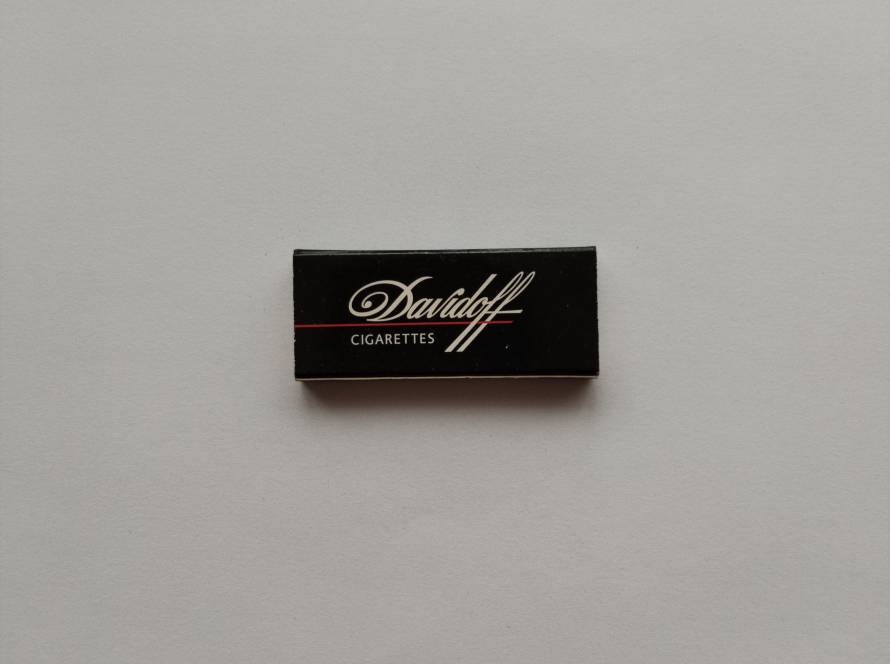 Black “Davidoff Cigarettes” matchbox with elegant white script logo and red accent line. Premium tobacco branding collectible, likely late 20th century.