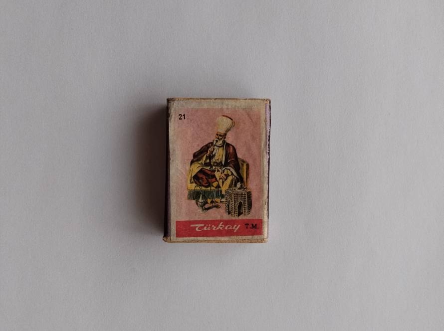 Türkay branded matchbox depicting a seated Ottoman elder figure with traditional attire. The illustration reflects cultural and historical representation of Ottoman society.