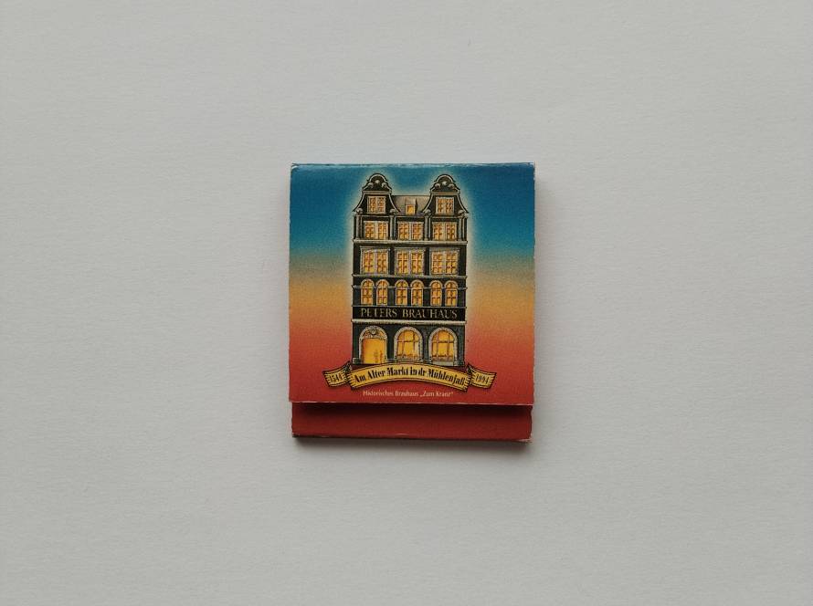 Colorful illustrated matchbox featuring historic Peters Brauhaus building; strong regional brewery identity.