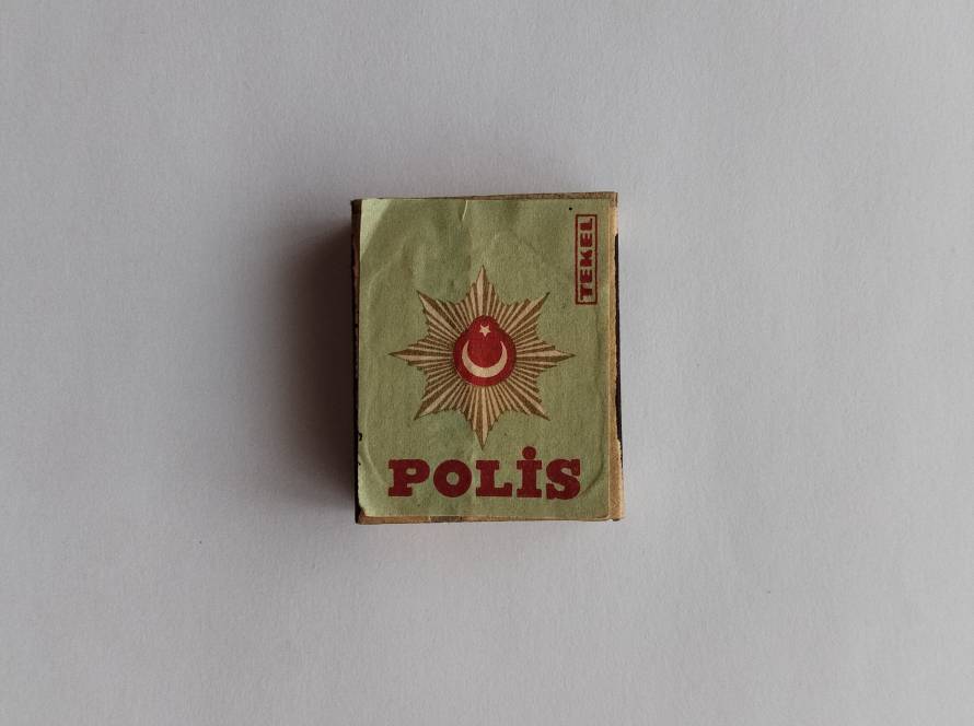 Retro matchbox label featuring a police emblem with crescent and star motif, symbolizing Turkish law enforcement.