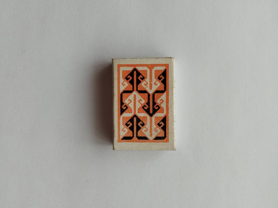 Tekel safety matchbox featuring orange and black Anatolian kilim-inspired geometric motif; reverse includes “Made in Turkey” and average contents information.