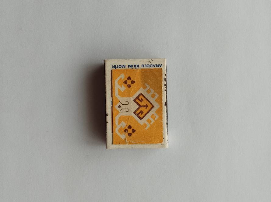 Tekel “Anadolu Kilim Motifi” matchbox featuring stylized Anatolian animal motif in yellow and brown tones; reverse includes 1986 production marking.