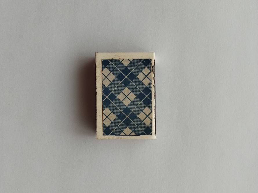 Tekel matchbox featuring blue plaid textile-style pattern design; reverse marked “İml. Tarihi 1986” with standard repeating Tekel logo background.