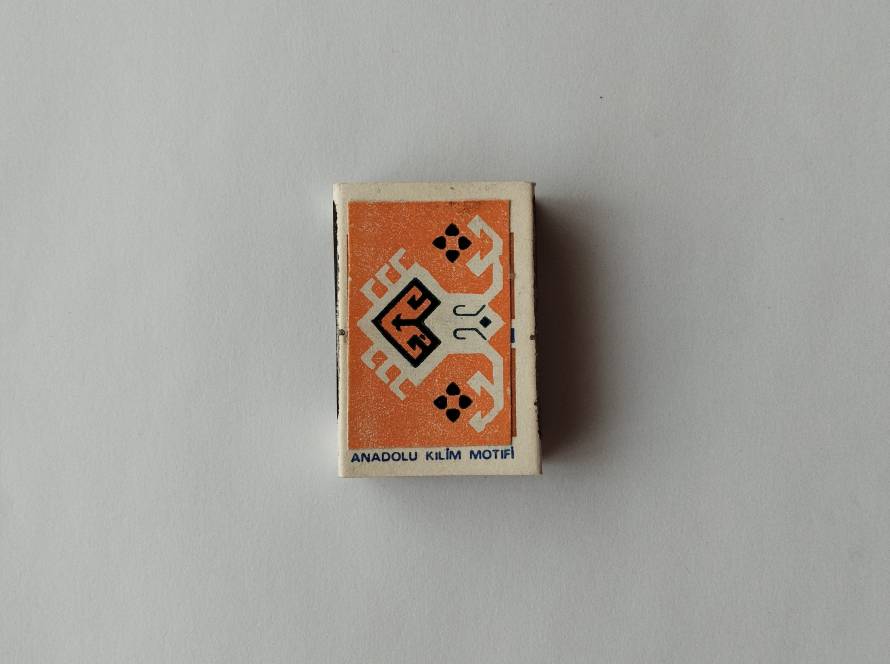 Tekel “Anadolu Kilim Motifi” matchbox featuring stylized orange Anatolian animal motif with geometric framing; reverse includes 1986 production marking.