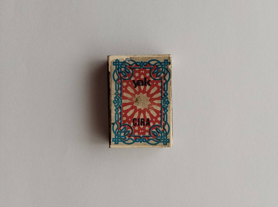 Yak Çıra Turkish matchbox with turquoise-red ornamental frame motif and geometric center design; reverse bears TEKEL tax print dated 1986.