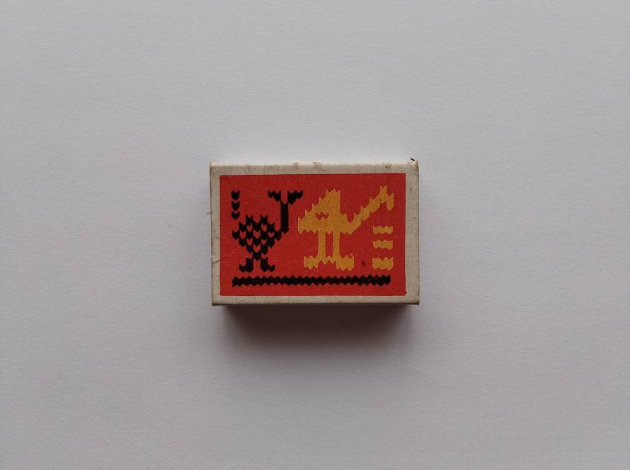 Decorative Türkay Kalite Kibrit matchbox with traditional Anatolian bird motif in black and yellow on red background; reverse shows Istanbul manufacturer branding and ornate floral frame pattern.
