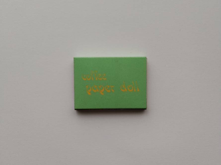 Promotional matchbox for Coffee Paper Doll featuring minimalist green design with decorative typography in English and Chinese.