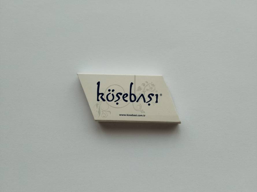 Köşebaşı restaurant promotional matchbox featuring the restaurant logo, decorative motif and official website address.