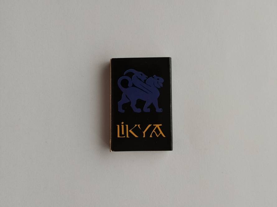 Black promotional matchbox featuring the Likya hotel branding and stylized mythological creature logo.
