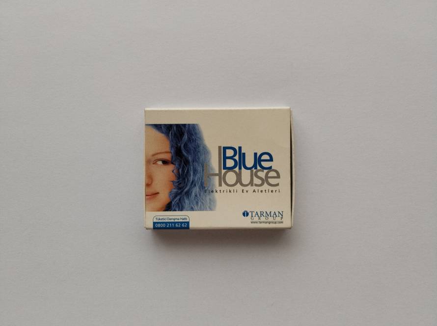 Advertising matchbox for Blue House electrical home appliances by Tarman Group, featuring a colorful promotional design and customer service information.