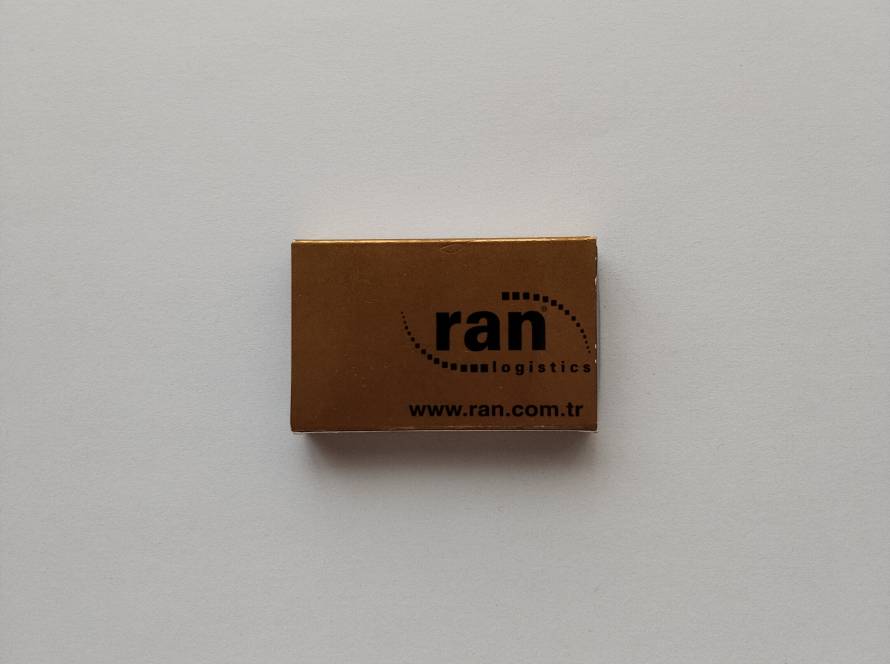 Advertising matchbox for RAN Logistics, featuring company branding and website information in a simple corporate style.