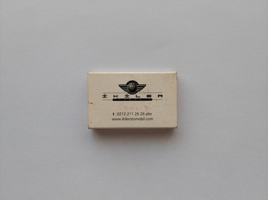 Advertising matchbox for İkiler Otomobil, displaying company logo, contact information, and website address.
