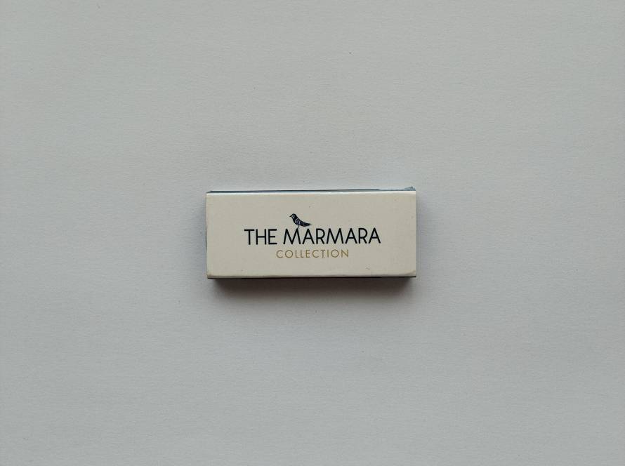 Promotional matchbox from The Marmara Collection hospitality group featuring minimalist branding and corporate website.
