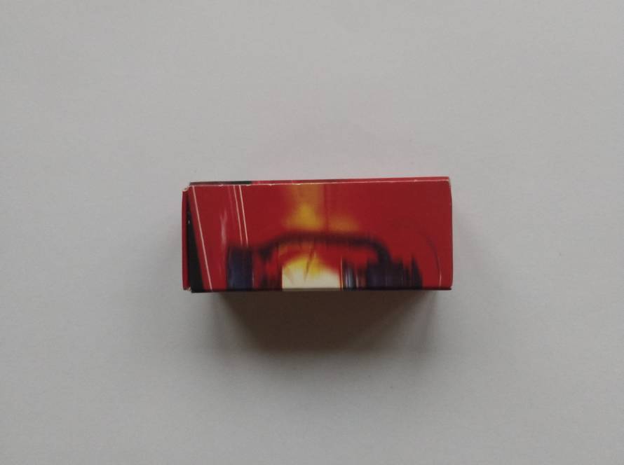Side views of a promotional matchbox featuring an abstract red-and-black graphic with a glowing lantern or light motif. No visible branding or identifying text is present on the photographed sides, preventing attribution to a specific company or venue.
