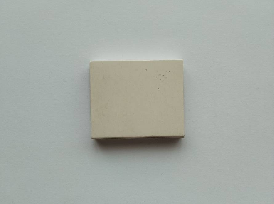 Plain front panel of a Cafe Brasil promotional matchbox. Cream-colored design with no printed branding on this side, showing light surface wear and minor marks consistent with age and handling.