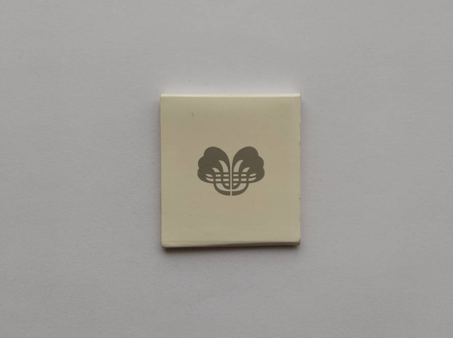 Minimalist cream-colored promotional matchbook featuring an unidentified gray abstract logo on the cover with a burgundy striker band. A clean, unbranded corporate design likely produced as promotional merchandise or hospitality advertising.