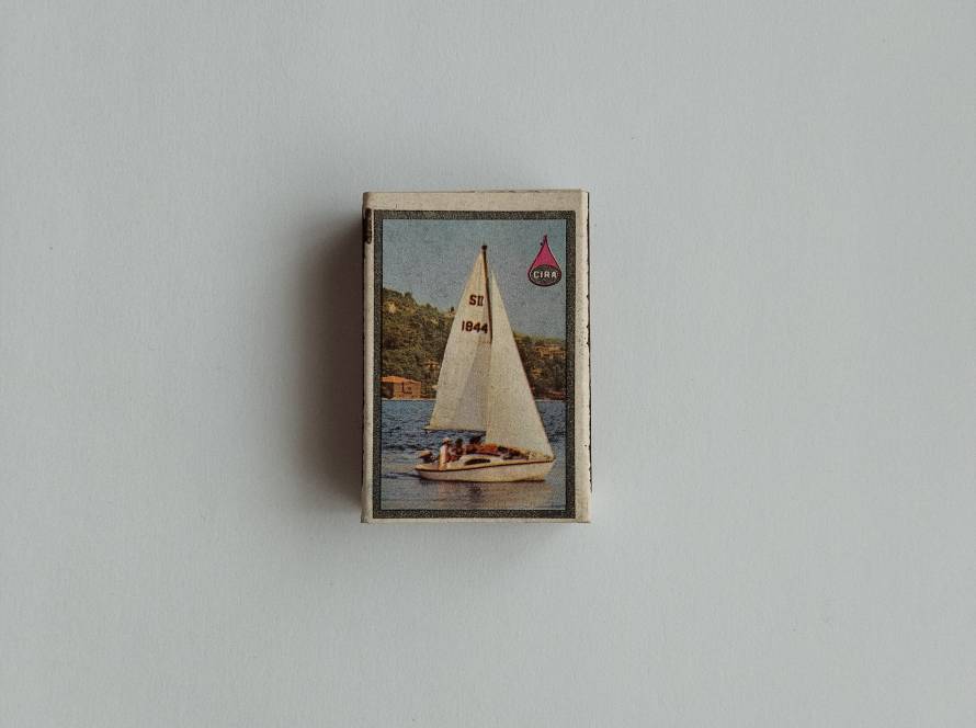Vintage promotional matchbox featuring a sailing yacht scene with CIRA branding and maritime-themed design.