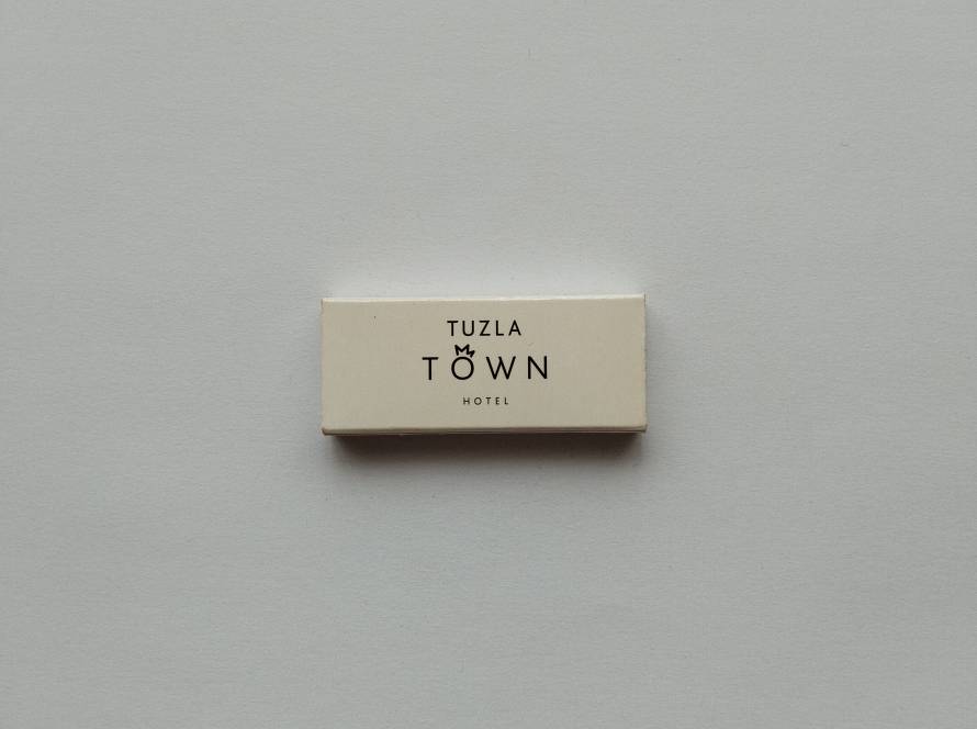 Minimalist promotional matchbox for Tuzla Town Hotel featuring clean modern typography and hotel branding on both sides.