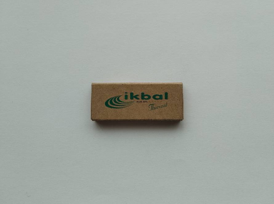 Eco-style kraft promotional matchbox for İkbal Deluxe Thermal Hotel, Afyonkarahisar, displaying the hotel logo on the front and contact information on the reverse.