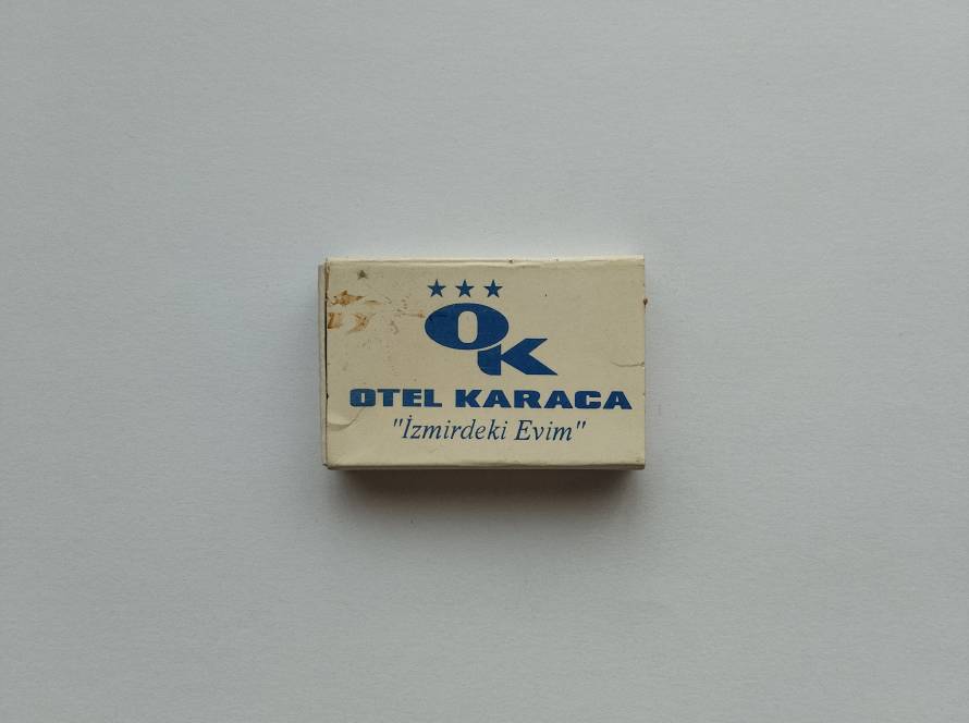 Promotional matchbox for Hotel Karaca, İzmir, featuring the slogan "İzmirdeki Evim" ("My Home in İzmir") on the front and hotel contact information on the reverse.