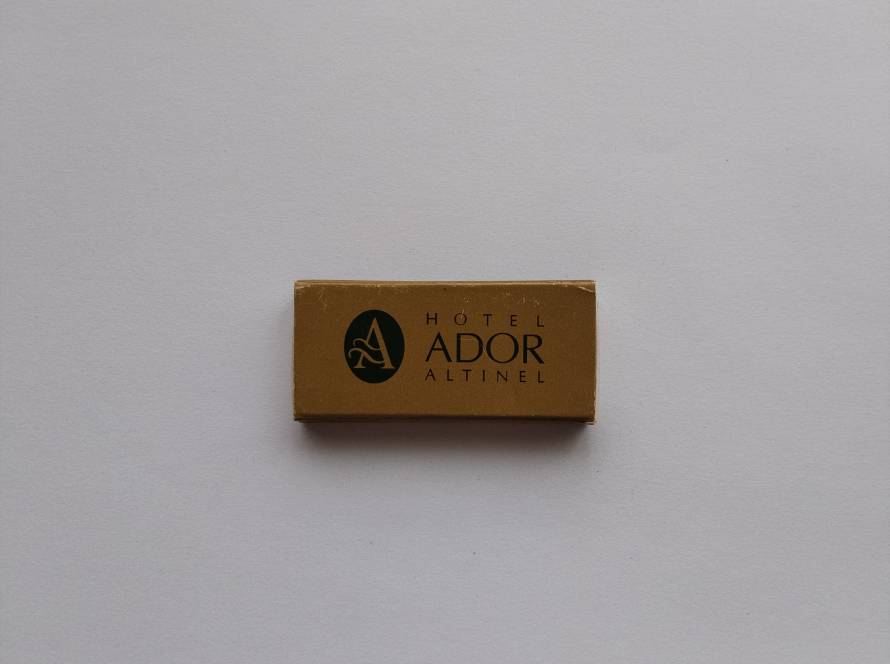 Promotional matchbox for Hotel Ador Altınel. Features a gold background with elegant hotel branding. Collectible Turkish hotel advertising piece.