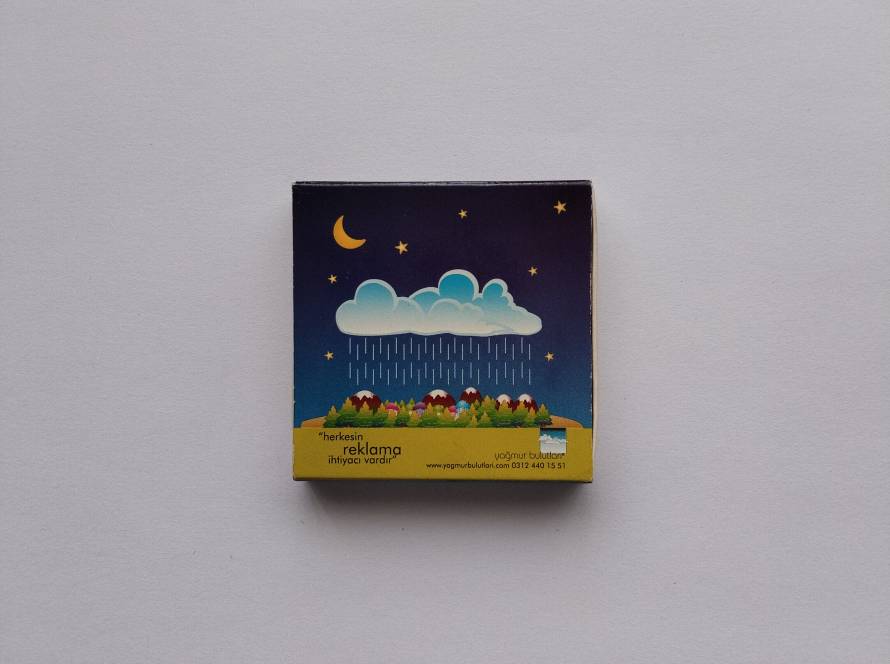 Promotional matchbox for Yağmur Bulutları Advertising Agency. Features a colorful illustrated landscape promoting advertising services.