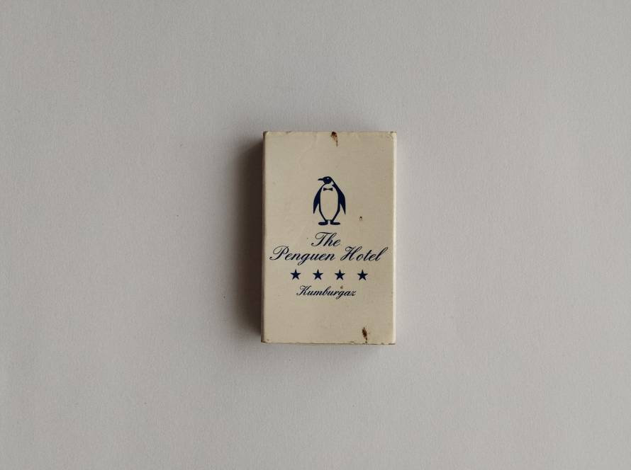 Reverse side of The Penguen Hotel promotional matchbox. Displays the hotel name and penguin logo on a minimalist design. Collectible hospitality advertising item.