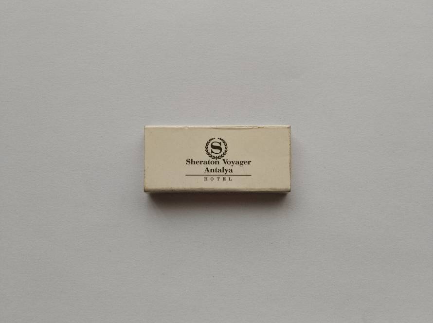 Promotional matchbox for Sheraton Voyager Antalya Hotel. Classic Sheraton logo with elegant minimalist design. Collectible Turkish hotel advertising piece.