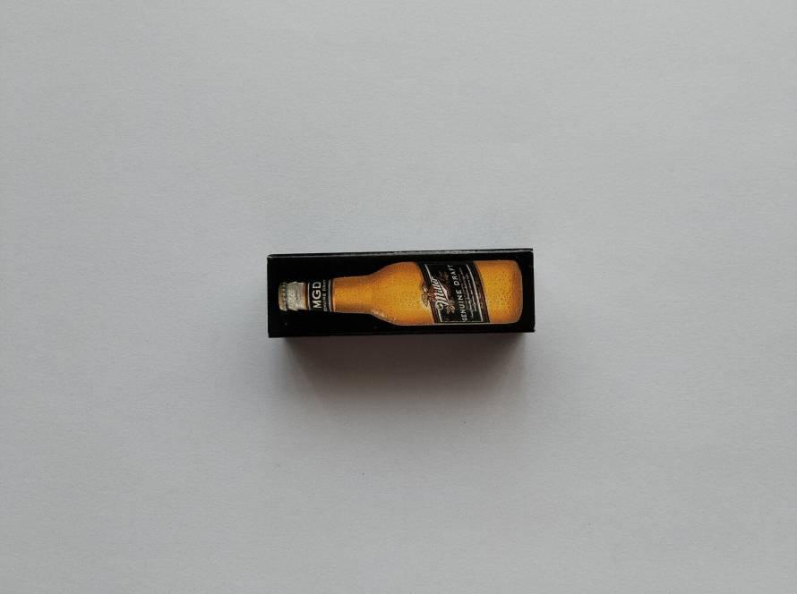 Black promotional matchbox featuring Miller Genuine Draft bottle illustration. Beverage advertising collectible.
