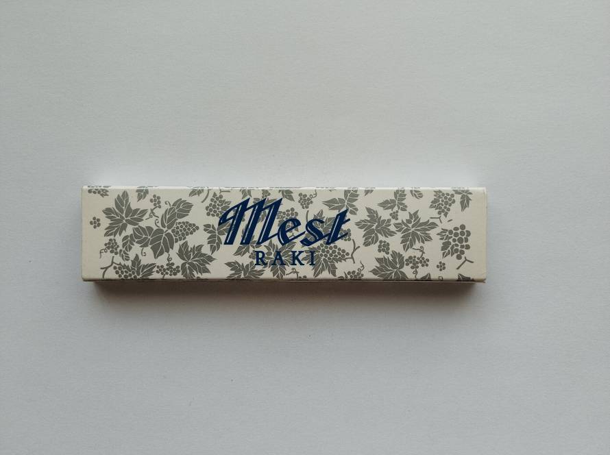 Promotional matchbox for Mest Rakı, decorated with an elegant grapevine pattern emphasizing the traditional Turkish spirit.
